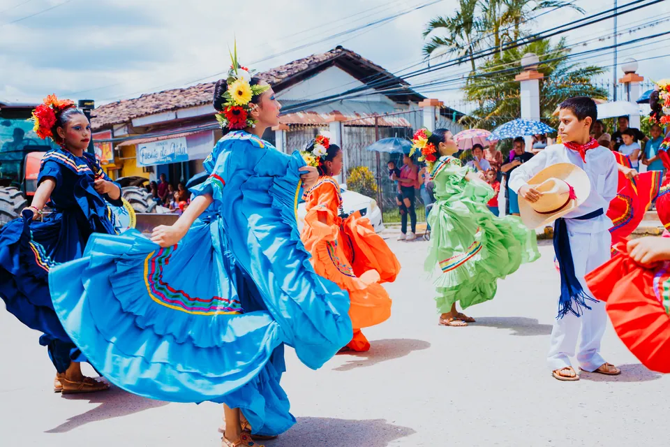 Bailarines con vestuario tradicional recorren una calle acompañados por el público